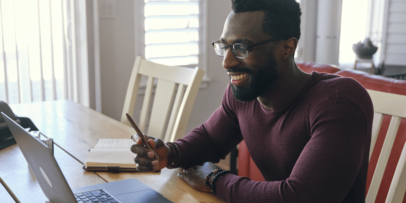 person sitting at a table at home and looking at laptop while on a video call