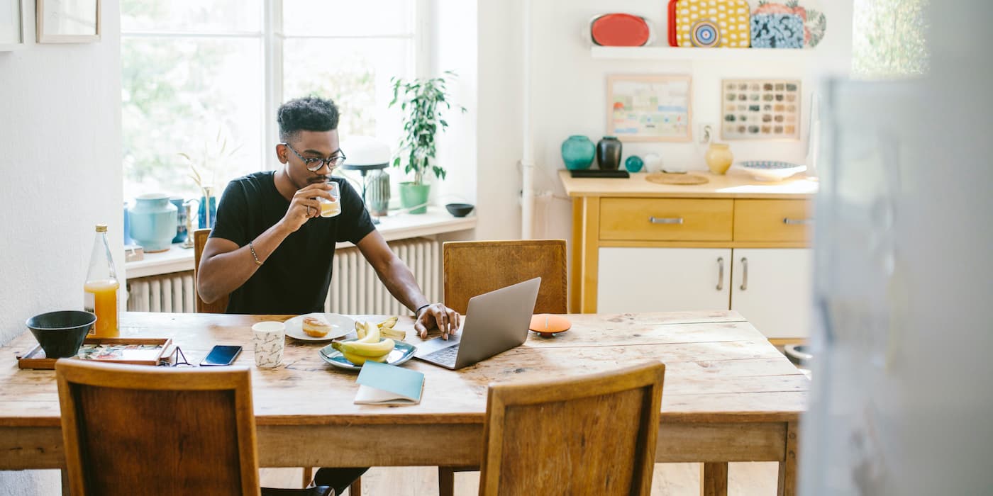 person drinking juice and working from dining room table