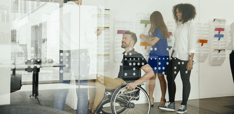 colleagues—including one in a wheelchair—talking in an office