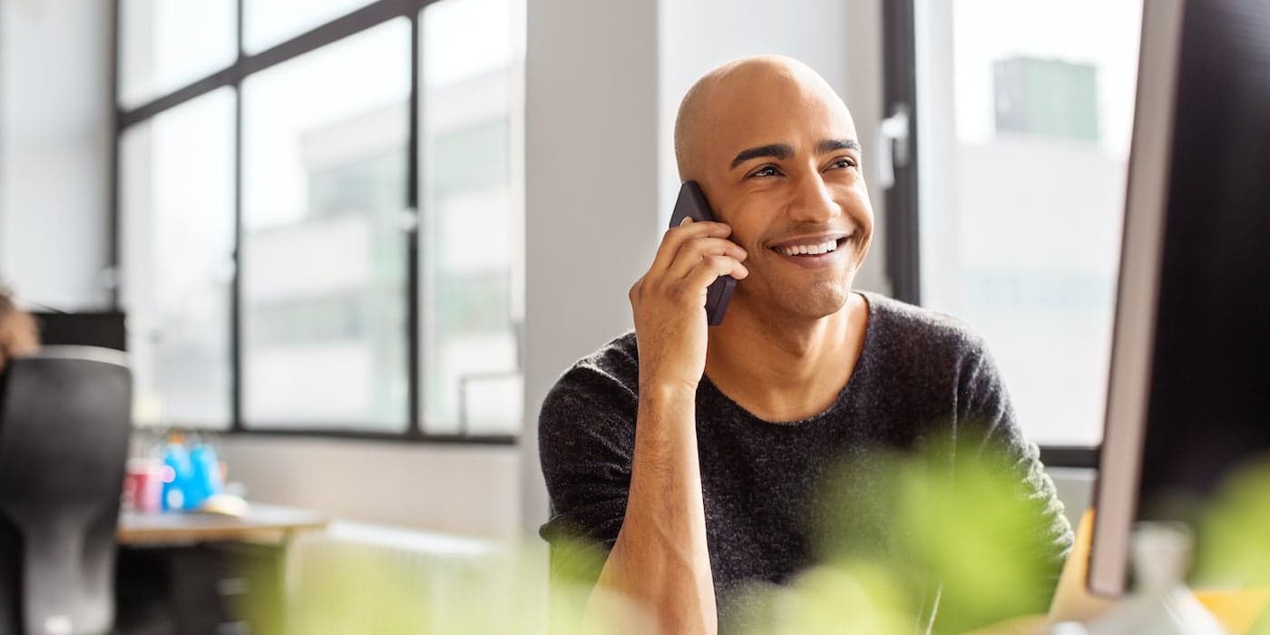 person sitting at a desk talking on the phone and smiling