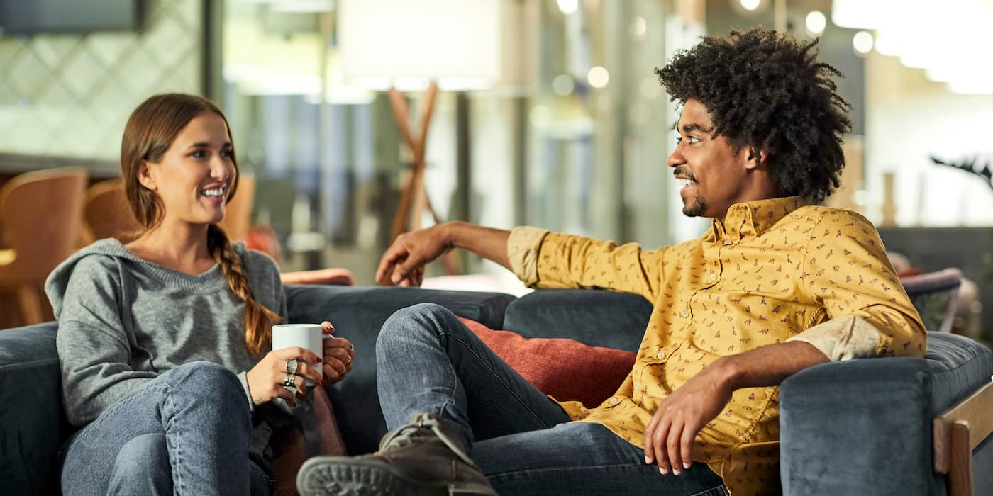 two coworkers sitting on a couch talking