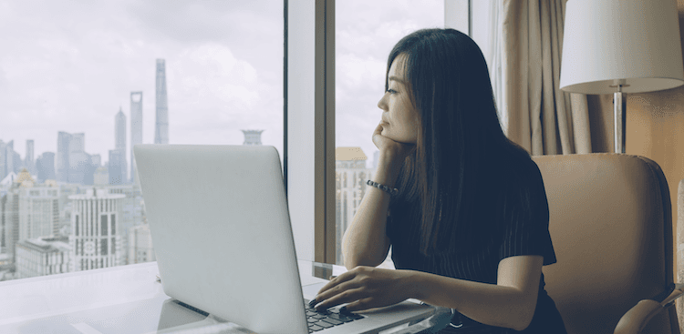 person sitting with laptop staring out the window