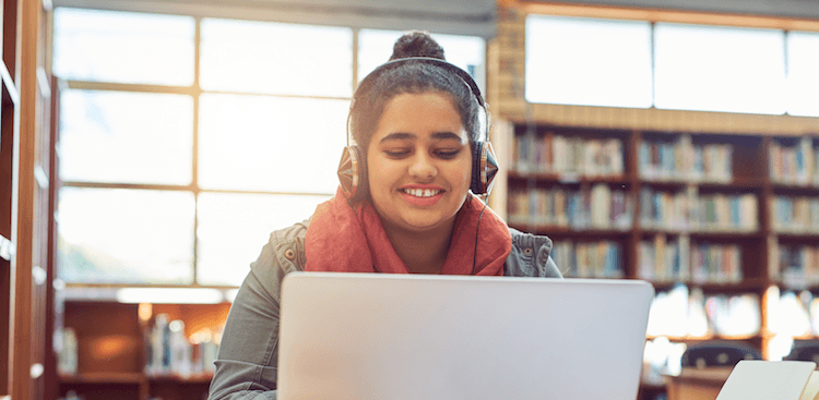 college student wearing headphones and working in the library